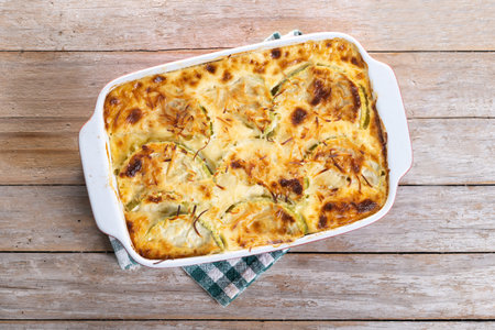 Casserole with cheese and gratin zucchini on wooden tableの写真素材