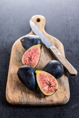 Fresh figs on cutting board on black stoneの写真素材