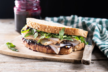 Turkey sandwich with cranberry sauce on wooden tableの写真素材