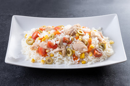 Rice salad with tomato, corn, olives on black slate backgroundの写真素材