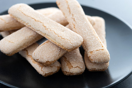 Italian biscuits ladyfingers savoiardi on black slate background
