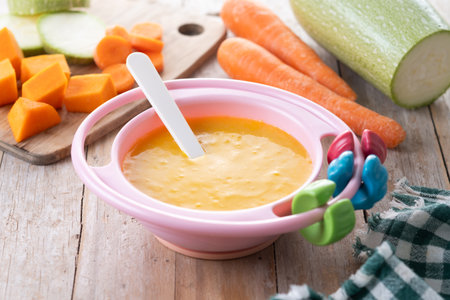 Bowl with baby food. vegetable puree on wooden tableの写真素材