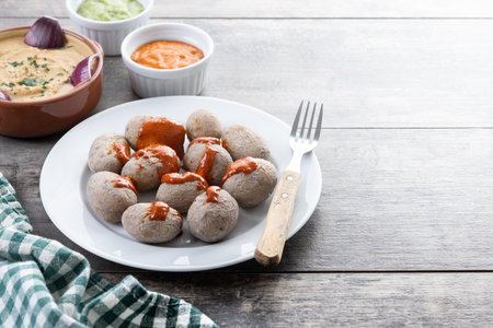 Papas Arrugadas with mojo and blanched gofio on wooden table. Traditional Canary Islands food.の写真素材