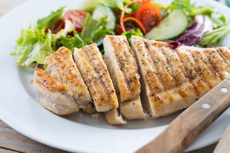 Healthy grilled chicken with salad on wooden tableの写真素材