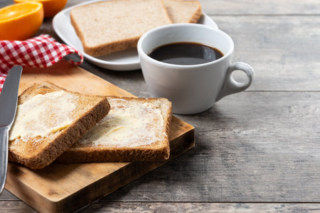 Sliced fresh bread with butter and coffee for breakfast on wooden table