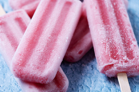 Red strawberry popsicles on blue background
