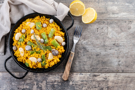 Traditional Valencian paella with rabbit, chicken, garrofon beans, snails, Moroccan green beans and saffron on wooden tableの写真素材