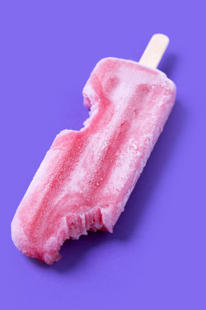 Red strawberry popsicles on purple background. Close up