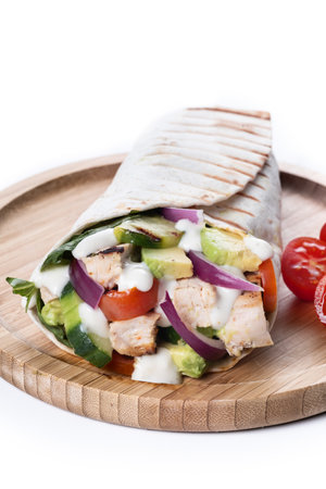 A delicious grilled chicken wrap filled with tender chicken, fresh vegetables, and a creamy dressing, all wrapped in a soft tortilla. Perfect for a quick lunch isolated on white backgroundの写真素材