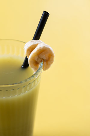 Green smoothie with spinach, banana, apple, and lemon on yellow backgroundの写真素材
