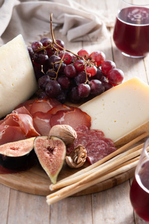 Charcuterie Board with Cheese, Grapes, and Figs on wooden tableの写真素材
