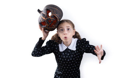 Girl in Halloween costume holding a Halloween pumpkin with surprised expression