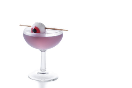 Purple Halloween cocktail garnished with candy eye isolated on white backgroundの写真素材