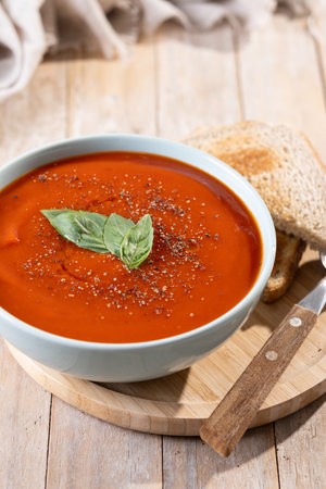Homemade Tomato Soup in bowl with Basil on wooden tableの写真素材