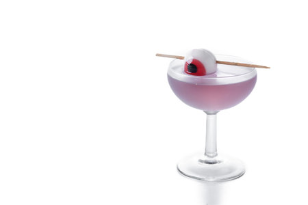 Purple Halloween cocktail garnished with candy eye isolated on white backgroundの写真素材