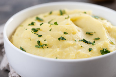 Mashed potatoes in white bowl on wooden table