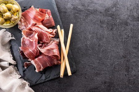Slices of Spanish Serrano Ham on black slate backgroundの写真素材
