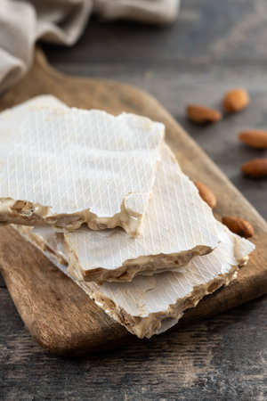 Traditional Christmas sweet, pieces of delicious almond nougat on wooden table (hard nougat)の写真素材