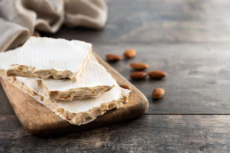 Traditional Christmas sweet, pieces of delicious almond nougat on wooden table (hard nougat)の写真素材