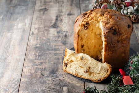 Traditional Italian Panettone on wooden table and christmas tree backgroundの写真素材