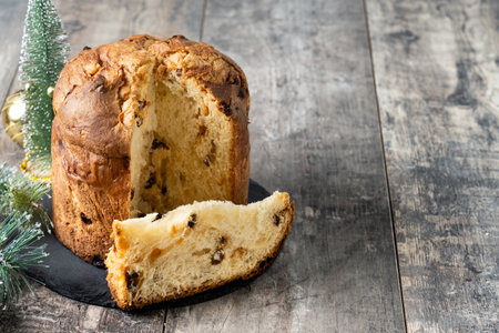 Traditional Italian Panettone on wooden table and christmas tree backgroundの写真素材