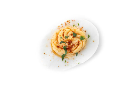 Homemade hard Boiled Deviled Eggs garnished with herbs isolated on white background. top view