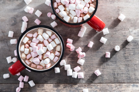 Hot chocolate drink with marshmallows in red mug on wooden tableの写真素材