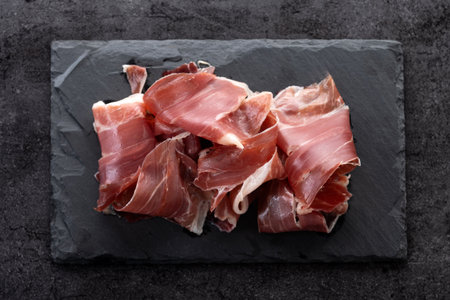 Slices of Spanish Serrano Ham on black stoneの写真素材