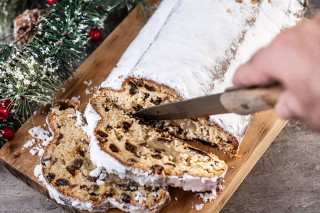 Traditional Christmas Stollen with Raisins and Powdered Sugar on wooden tableの写真素材