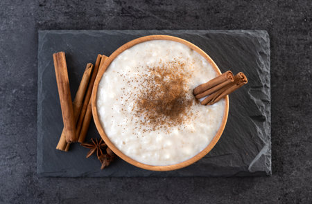 Rice pudding on wooden bowl on black slate background