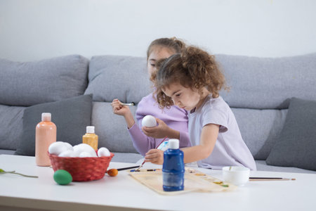 Two sisters decorating Easter eggs.at home