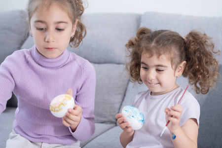 Two sisters decorating Easter eggs.at homeの写真素材