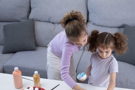 Two sisters decorating Easter eggs.at homeの写真素材