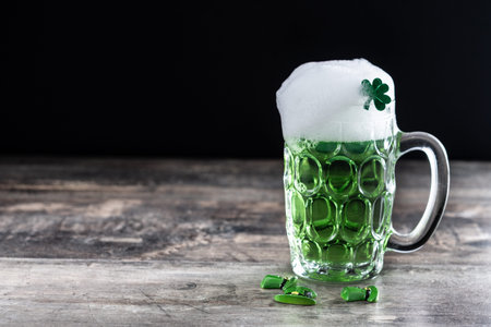 Green beer mug with foam for St. Patrickâ€™s Day on wooden table
