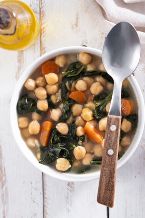 Chickpea and Spinach Soup with Carrots in White Bowl on wooden tableの写真素材