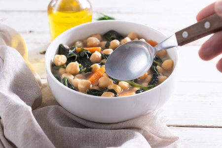 Chickpea and Spinach Soup with Carrots in White Bowl on wooden tableの写真素材