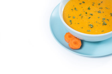 Creamy carrot soup in Blue Bowl isolated on white backgroundの写真素材