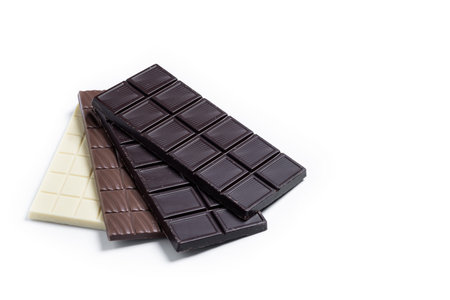 Assortment of white, milk and dark chocolate pieces on white background