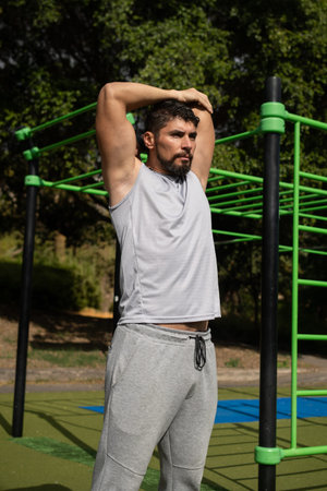 Young athletic man stretching in a park before exercising. Healthy lifestyle, outdoor fitness...
