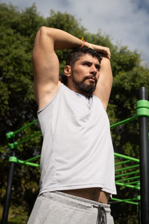 Young athletic man stretching in a park before exercising. Healthy lifestyle, outdoor fitness...
