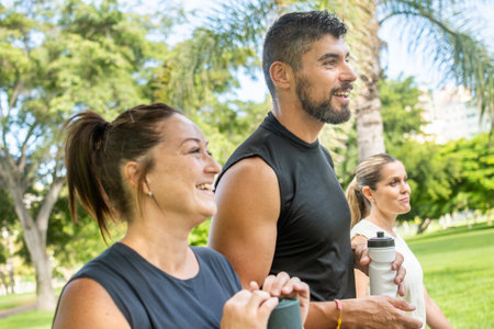 Friends walking together in a park carrying yoga mats after an outdoor fitness session. Healthy lifestyle and friendship concept.