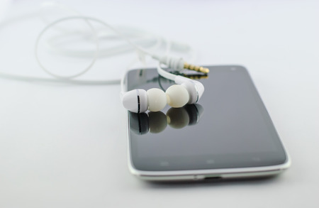 Small headphones with mobile phone on white backgroundの写真素材