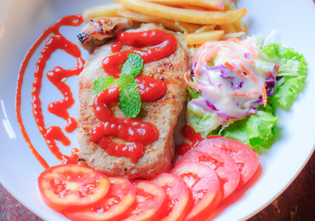 Beautiful pork steak with vegetables and sauce on a plateの写真素材