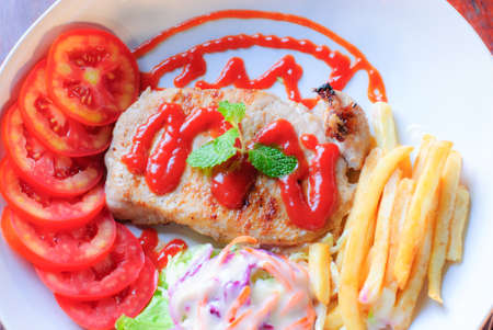 Beautiful pork steak with vegetables and sauce on a plateの写真素材