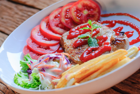 Beautiful pork steak with vegetables and sauce on a plateの写真素材