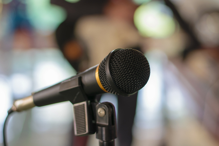 Microphone in concert hall or conference room with defocused person in backgroundの写真素材