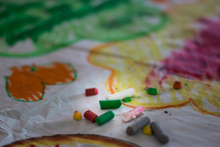 Crayons lying on an abstract hand drawing backgroundの写真素材