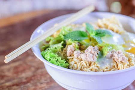 Chinese noodles with minced pork and egg in bowl on wooden tableの写真素材