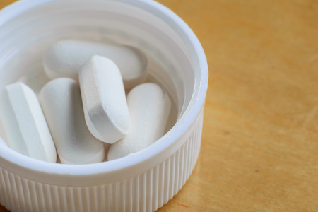Closeup of some white pills on wood