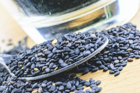 Black sesame seeds. Healthy sesame seeds in spoon on wooden tableの写真素材